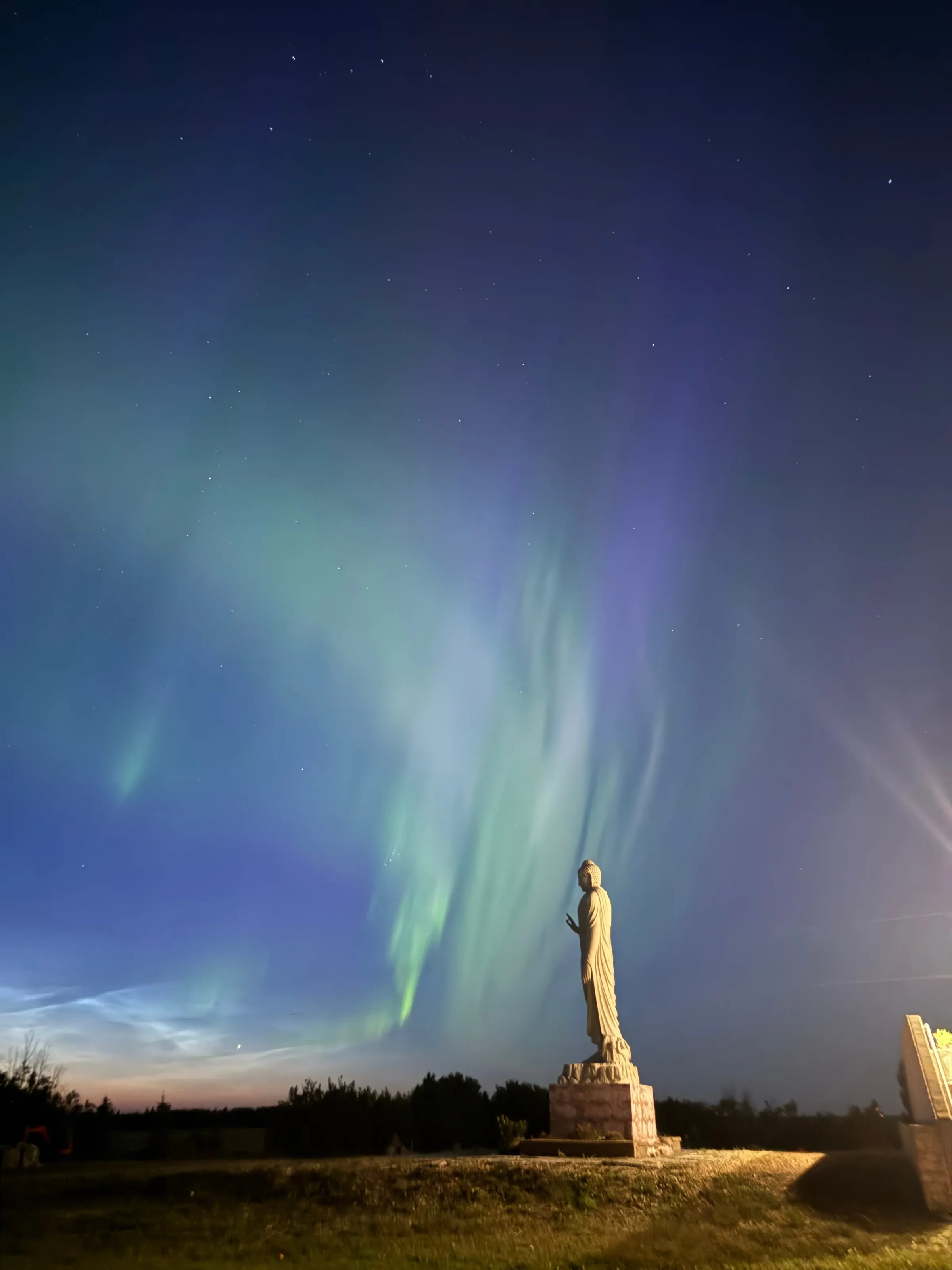 The northern lights above a statue on the retreat grounds at night.