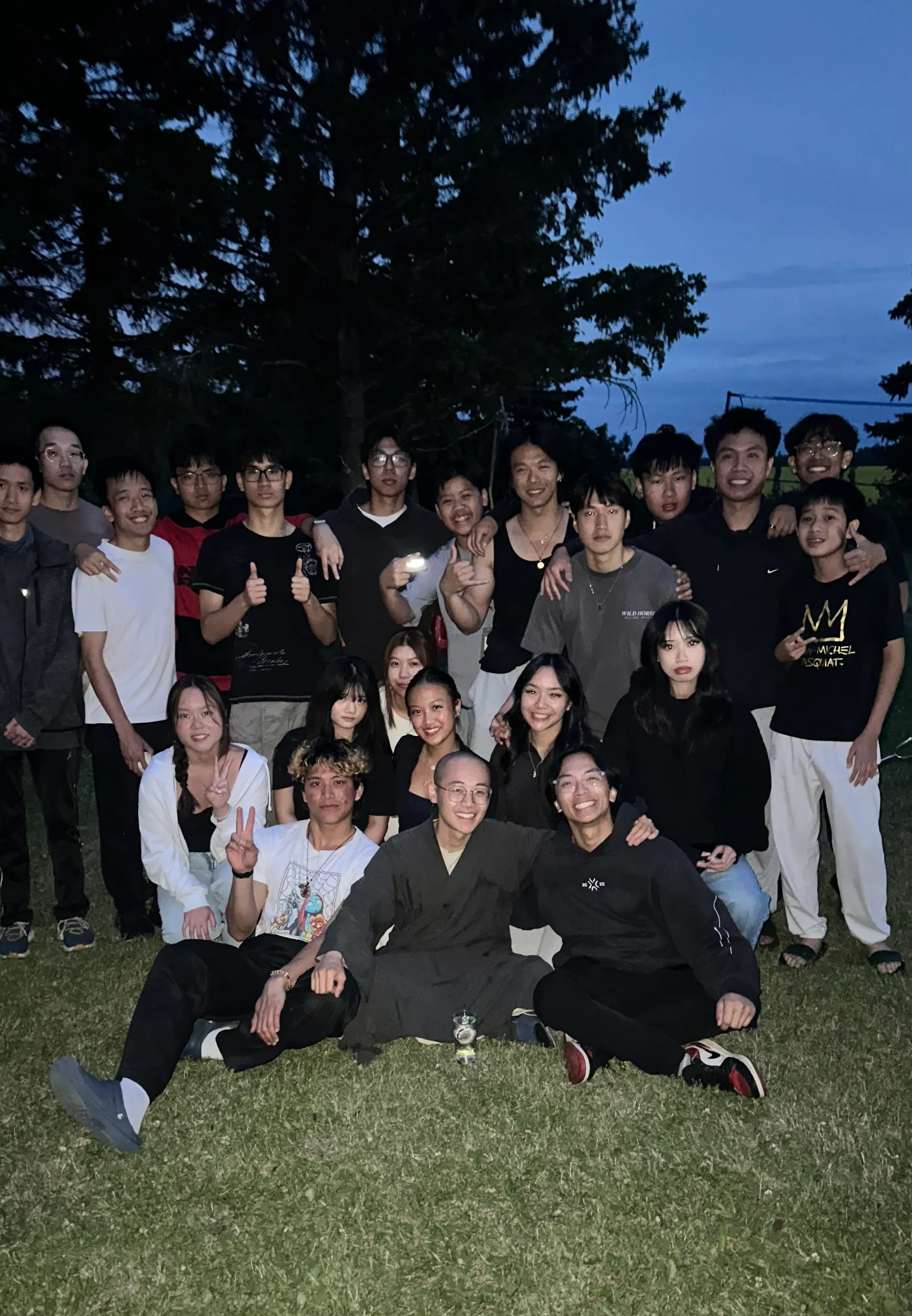 A group photo of retreat participants on the lawn at dusk.